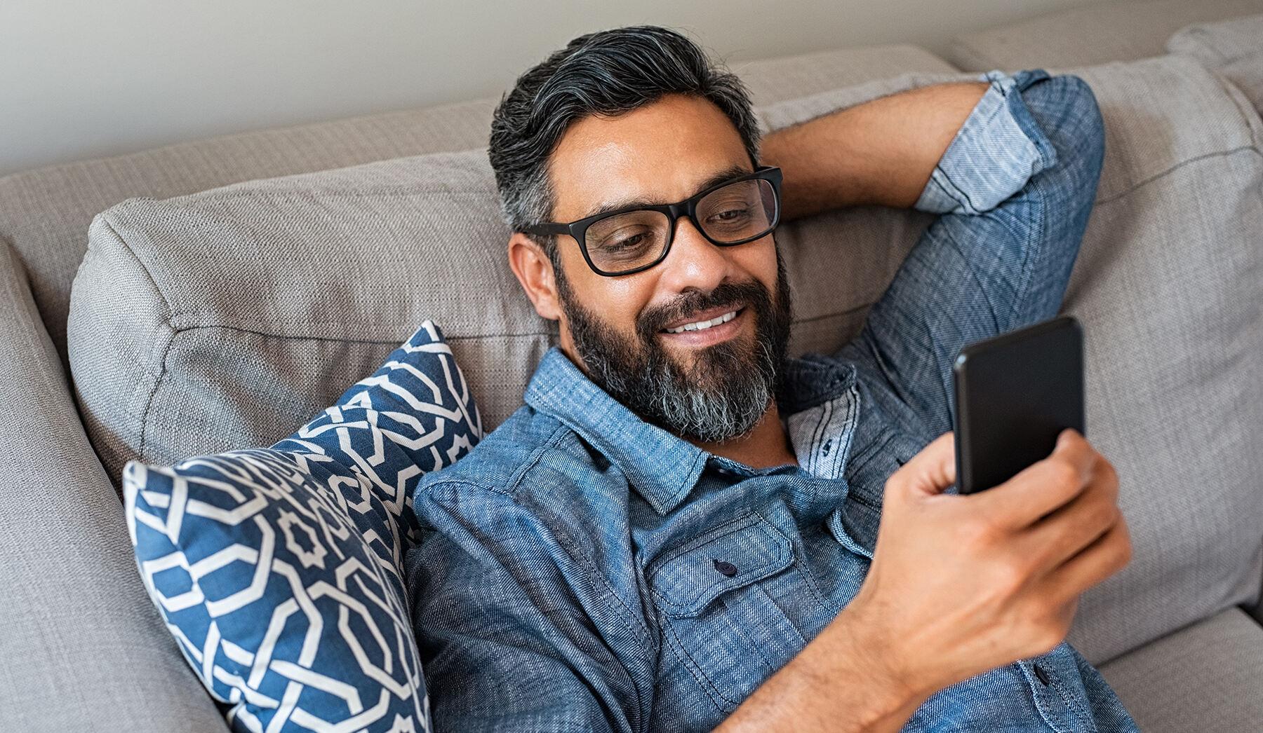 man looking at a phone sitting in a couch
